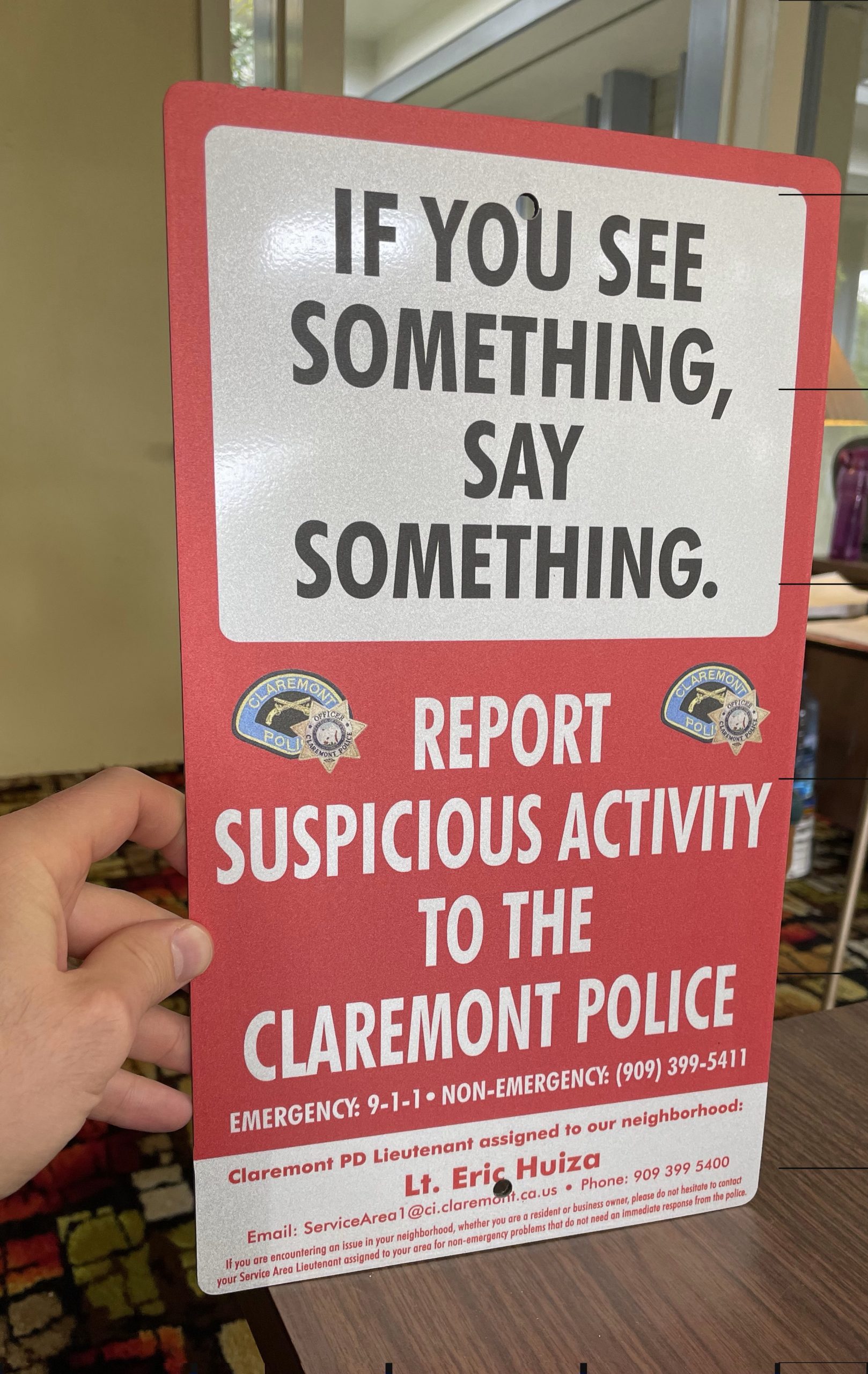 Parking lot signs for Claremont displaying the words "See Something Say Something." The public safety signs show the contact information of local authorities.