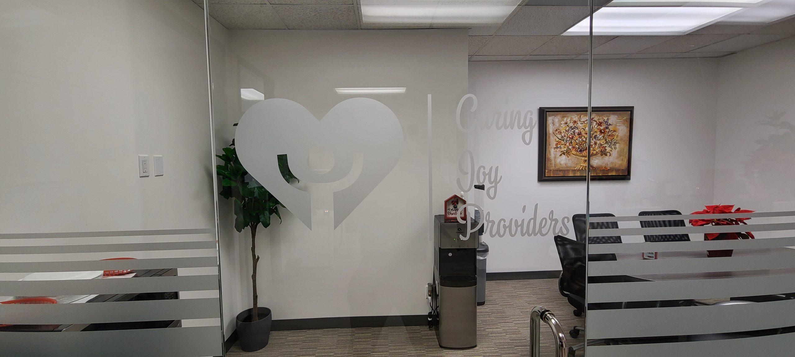 Frosted window vinyl can add to the appearance of an office and also display brand logos. Like these window graphics for Caring Joy Providers in Encino.