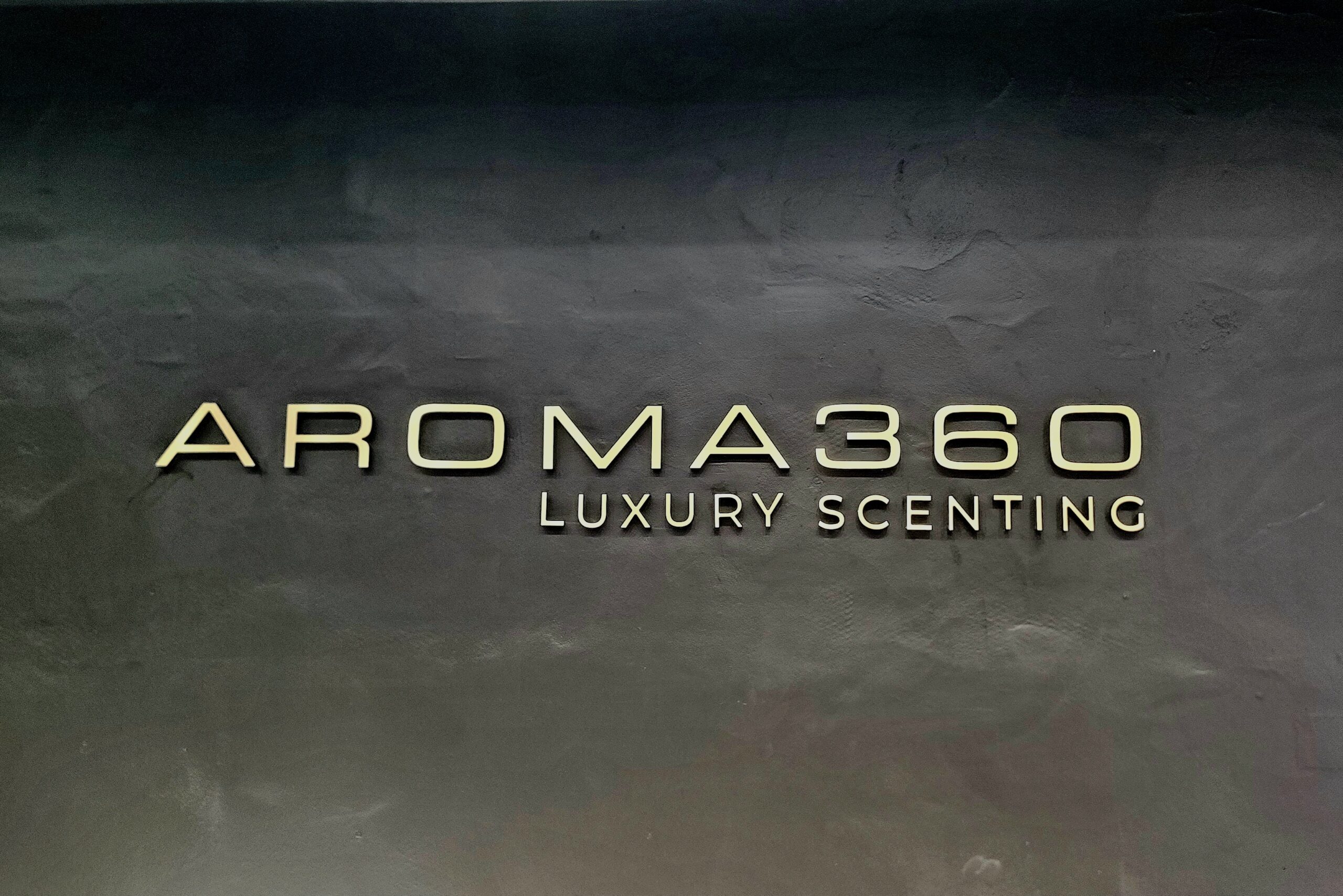 Aroma 360 Indoor Sign - Elegant brushed light brass indoor sign showcasing AROMA 360.