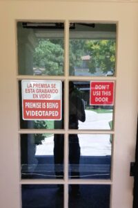  A Wayfinding and Directional Signs sign at Casa Gateway with the text "LA PREMISA SE ESTA GRABANDO EN VIDEO" and "DON'T USE THIS DOOR" on it.
