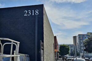 A photo of the number "2318" crafted from metallic silver acrylic, installed on a building facade. The numbers are approximately 18 inches tall and cast subtle shadows, showcasing their dimensionality.