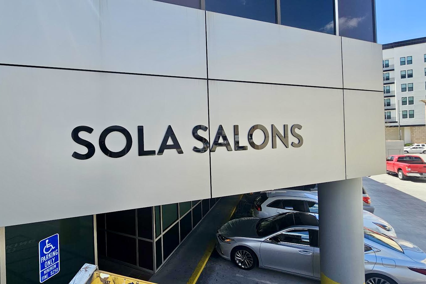 Sleek black dimensional letters spelling out "Sola Salons" on a cream background.