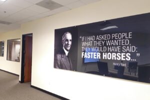 Image of A large clear acrylic panel with a quote by Henry Ford directly printed on the subsurface, with flood white ink. The panel is router-cut with holes for standoffs