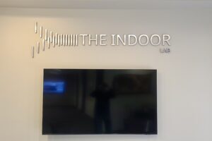 Image of A brushed metal lobby sign that says "THE INDOOR LAB" in large letters, with the company's logo below