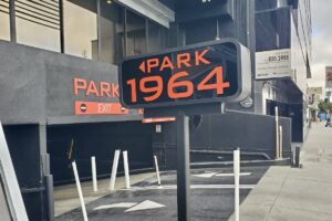 Red and white parking sign with the letter "P" and "1964" on the 1964 building.