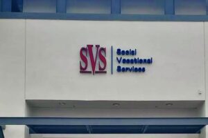 Close-up of the SVS channel letter sign with red and blue letters against a light building facade.