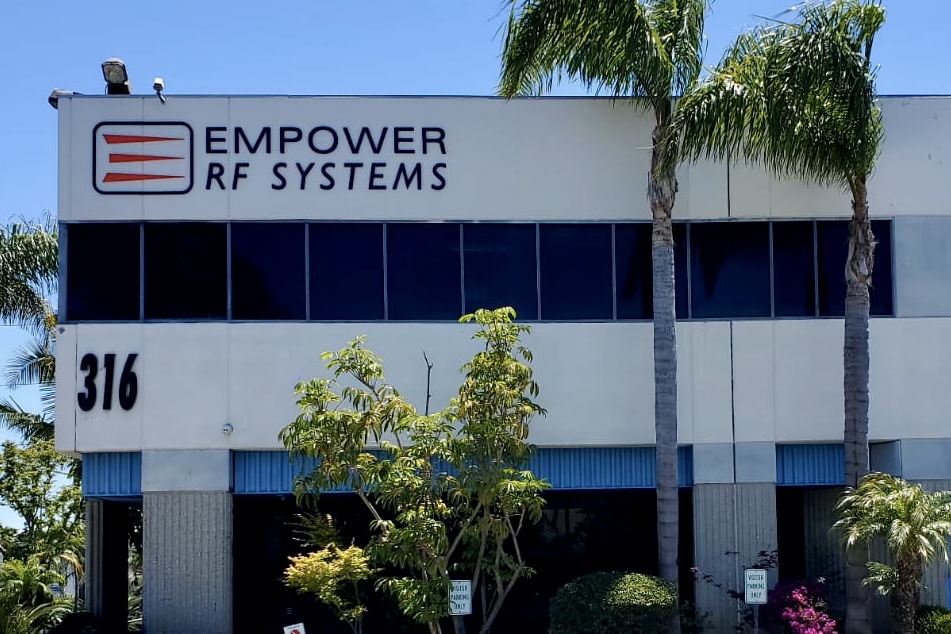 A brick wall supports a sizable dimensional letter sign. The sign is adorned with vibrant acrylic letters spelling "Empower RF Systems," and prominently showcases the company logo at the center.