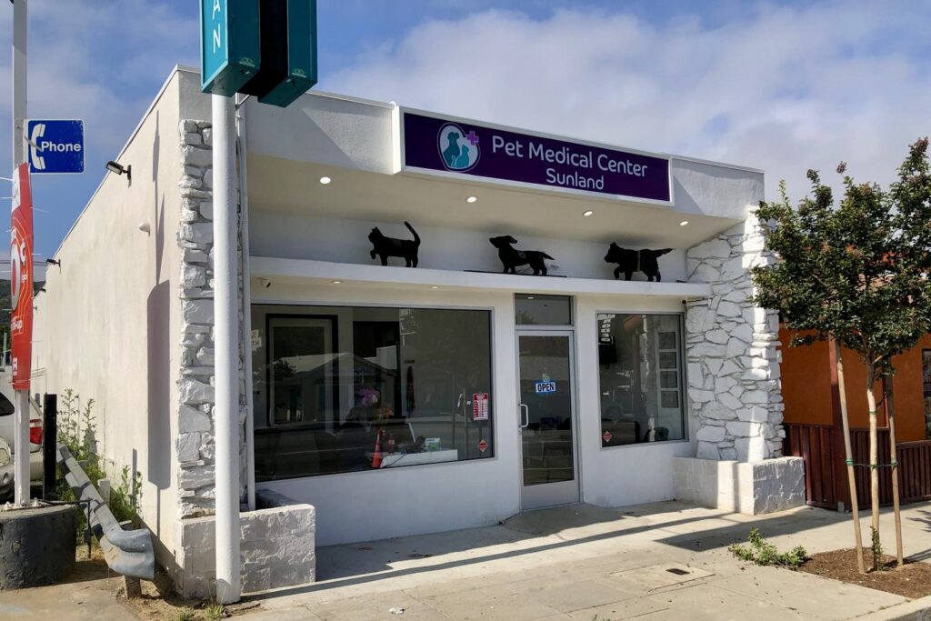 Illuminated lightbox sign for Pet Medical Center Sunland, displaying clinic name and logo above entrance