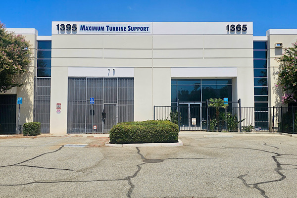 An expansive view of the Maximum Turbine Support headquarters in Riverside, featuring a massive three-panel Dibond outdoor sign dominating the facade. The sign's scale creates a powerful visual impact against the Inland Empire skyline.
