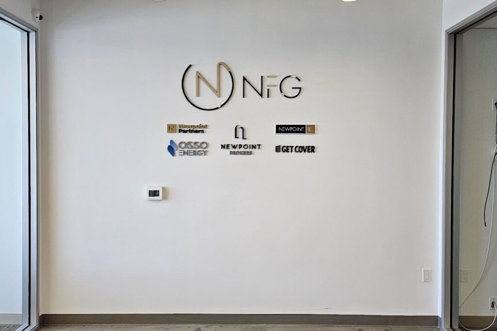 The camera captures a wide shot of the impressive NFG logo sign proudly displayed on the wall. Its considerable size and elegant brushed gold finish combine to make a visually stunning statement.