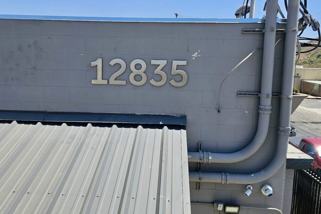 A close-up view of the Deveraux Specialties address sign. The sign is crafted from brushed stainless steel and features the address "12835" in bold, easy-to-read numbers with a minimum height of 12 inches.
