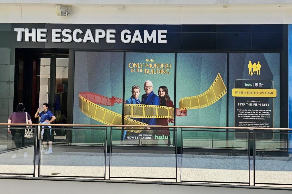 A wide shot of the Escape Game Century City storefront adorned with captivating wall and window graphics. The graphics capture the essence of the Only Murders in the Building series.
