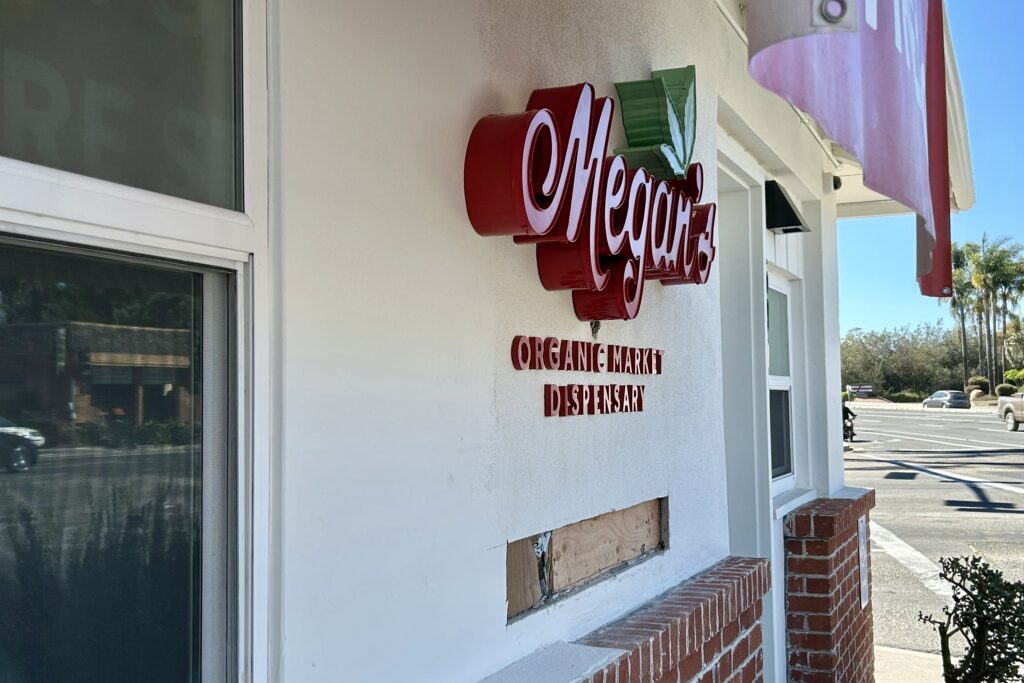 Close-up of front-lit channel letters for Megan Organic Market in vibrant red and green, featuring a carved leaf element.
