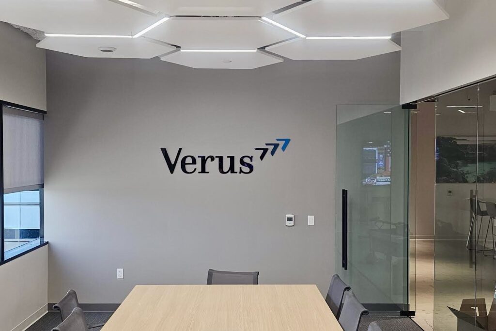 Wide shot of a conference room door with dimensional letters spelling "Verus" mounted above it. The letters are crafted from high-quality acrylic and complement the overall office aesthetic.