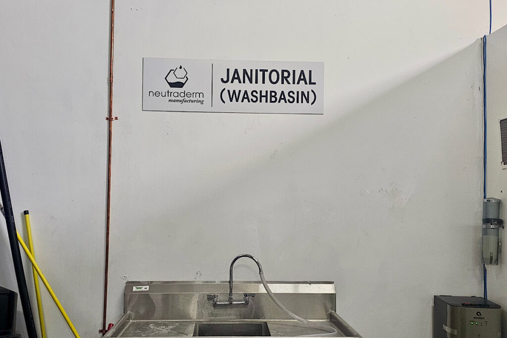 Janitorial washbasin ADA-compliant signage at Neutraderm, designed for durability and ease of identification.