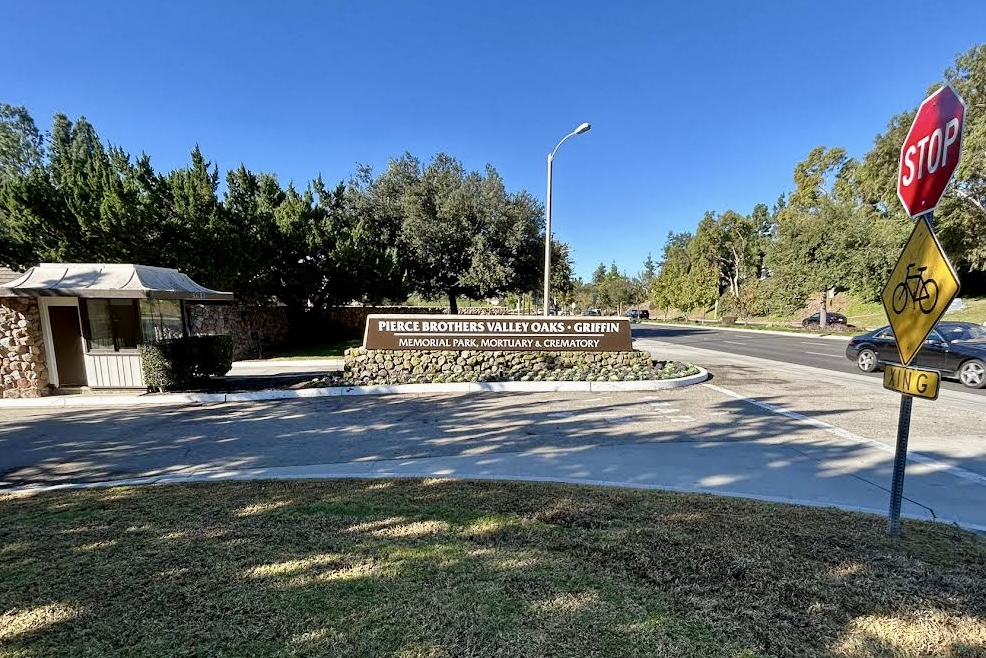 A wide shot of the Pierce Brothers Valley Oaks monument sign, showcasing its prominent placement and the surrounding landscaping. The sign features white lettering against a dark background, creating a strong visual impact.