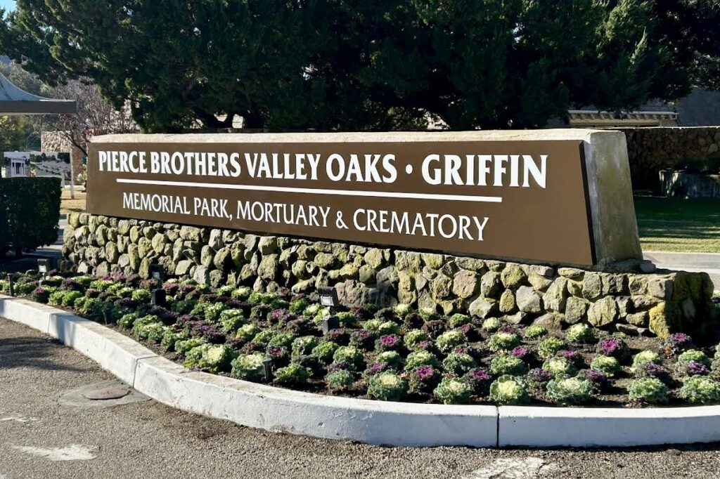 Close-up of the Pierce Brothers Valley Oaks monument sign, showcasing the elegant typography and the combination of white lettering on a dark brown background.