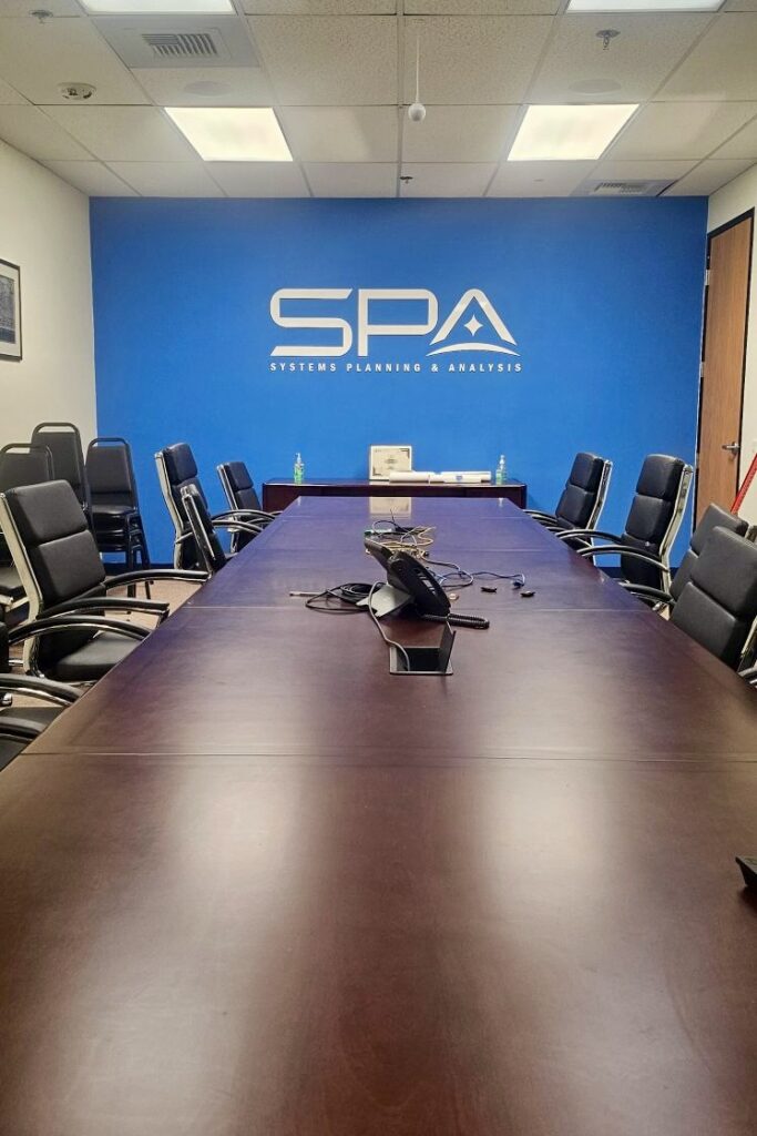 A wide view of the "SYSTEMS PLANNING & ANALYSIS" lettering on the boardroom sign, highlighting the precision of the cut acrylic.  