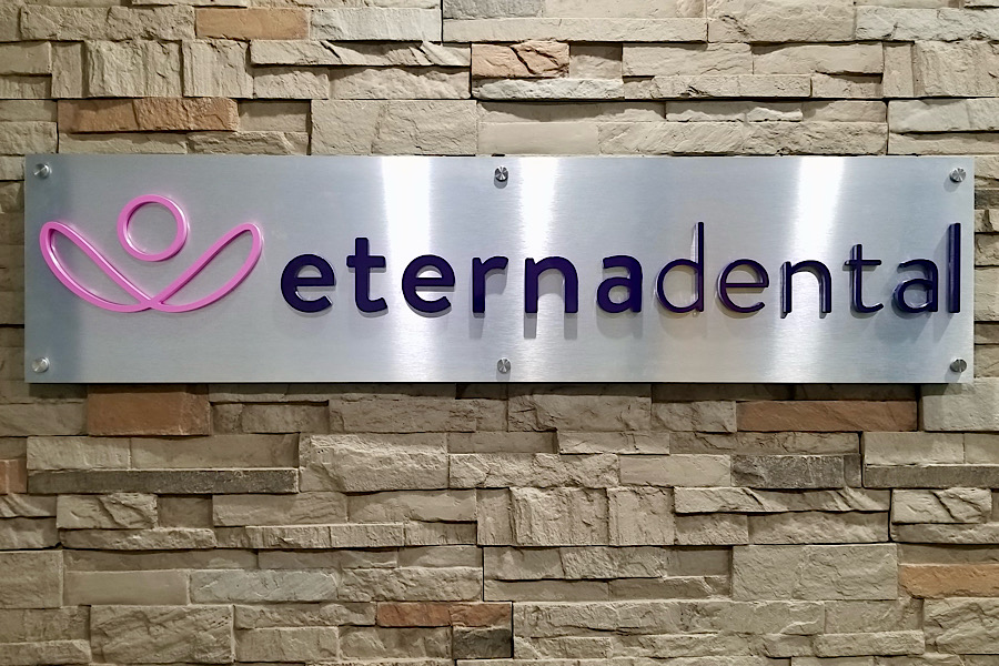 Photo of Eternadental’s lobby sign brings their brand to life. With a brushed metal background and dimensional acrylic letters and logo. 