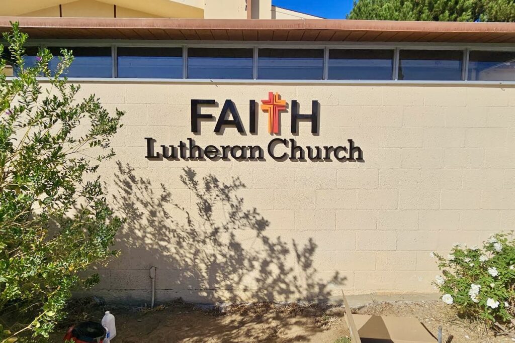 The Faith Lutheran Church’s durable outdoor church sign, emphasizing the ¾ inch thick precision-cut letters and the beautifully painted cross logo. The image highlights the quality and craftsmanship of the sign.