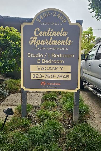 Closeup of the Spring Property Group Apartment Signage. Black lusterboard with gold trim and lettering.