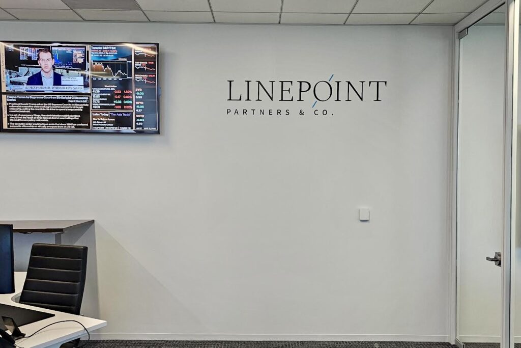 Professional office signage installation for a financial or consulting firm in a sleek, minimalist office lobby.