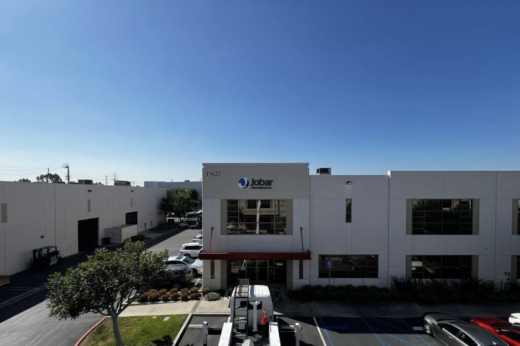 Wide shot of Jobar International, Inc., showcasing its corporate signage in Torrance from afar. The structure contrasts with trees, vehicles, and adjacent properties.