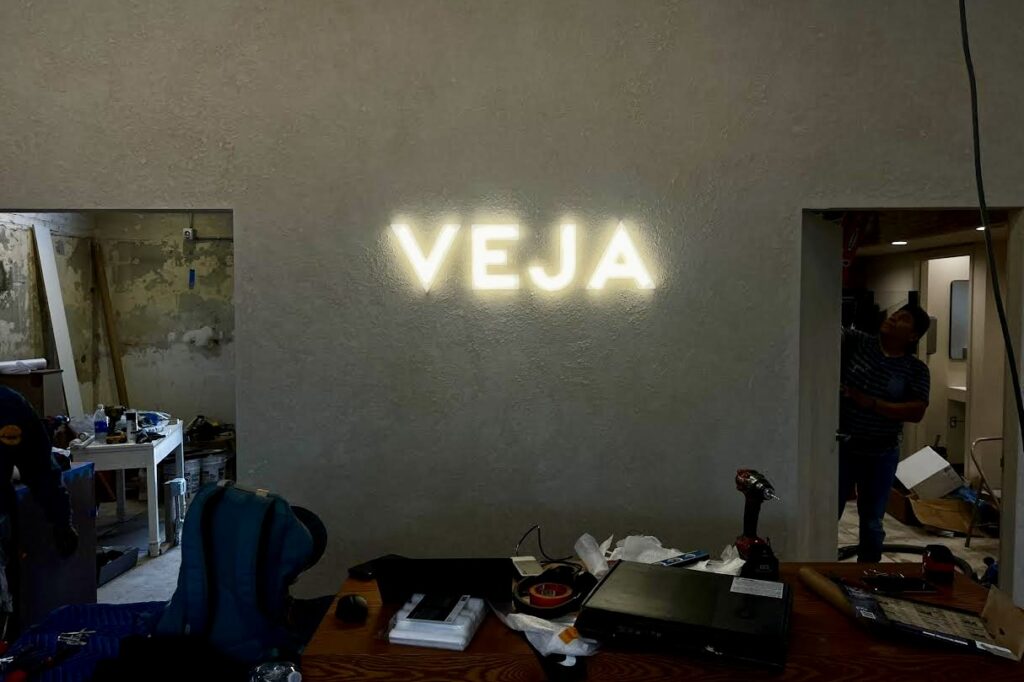 A view of the Veja retail signage interior LED 3000K warm glow logo on their back wall.